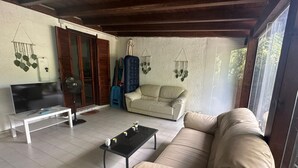A living room with a sofa, a coffee table, a TV on a stand, and a fan. - Villa 'Casa Le Palme' with Sea View, Wi-Fi and Air Conditioning (GEREMEAS RESIDENCE)