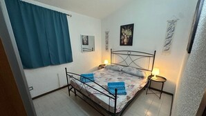 A bedroom with a bed, two bedside tables, a window with curtains, and wall art. - Villa 'Casa Le Palme' with Sea View, Wi-Fi and Air Conditioning (GEREMEAS RESIDENCE)