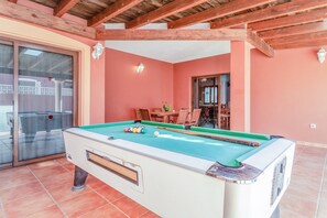 A pool table in a room with wooden beams, a glass door, and a red wall. - Spacious villa "Don Rodrigo" with Wi-Fi, garden, terrace and pool (Corralejo)