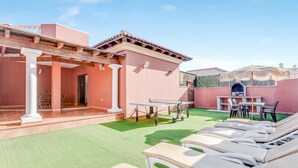 Een terras met loungezetels, een tafel en een pergola.
