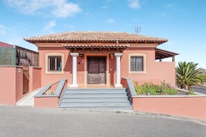 A two-story building with a tiled roof, a wooden door, and a set of stairs leading to the entrance. - Spacious villa "Don Rodrigo" with Wi-Fi, garden, terrace and pool (Corralejo)