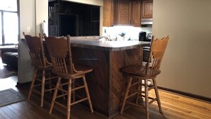Una cocina con una isla central, sillas de madera y armarios empotrados.