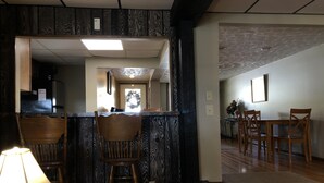 Una cocina con barra de madera, sillas y una zona de comedor con mesa y sillas.