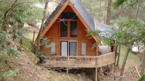 A wooden cabin with a balcony, surrounded by trees.