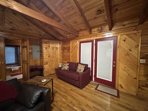 Un interior de madera con un sofá, una mesa y un ventanal.
