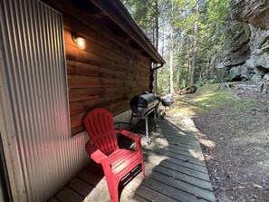 Eine Holzhütte mit einem roten Stuhl und einem Grill vor der Tür.