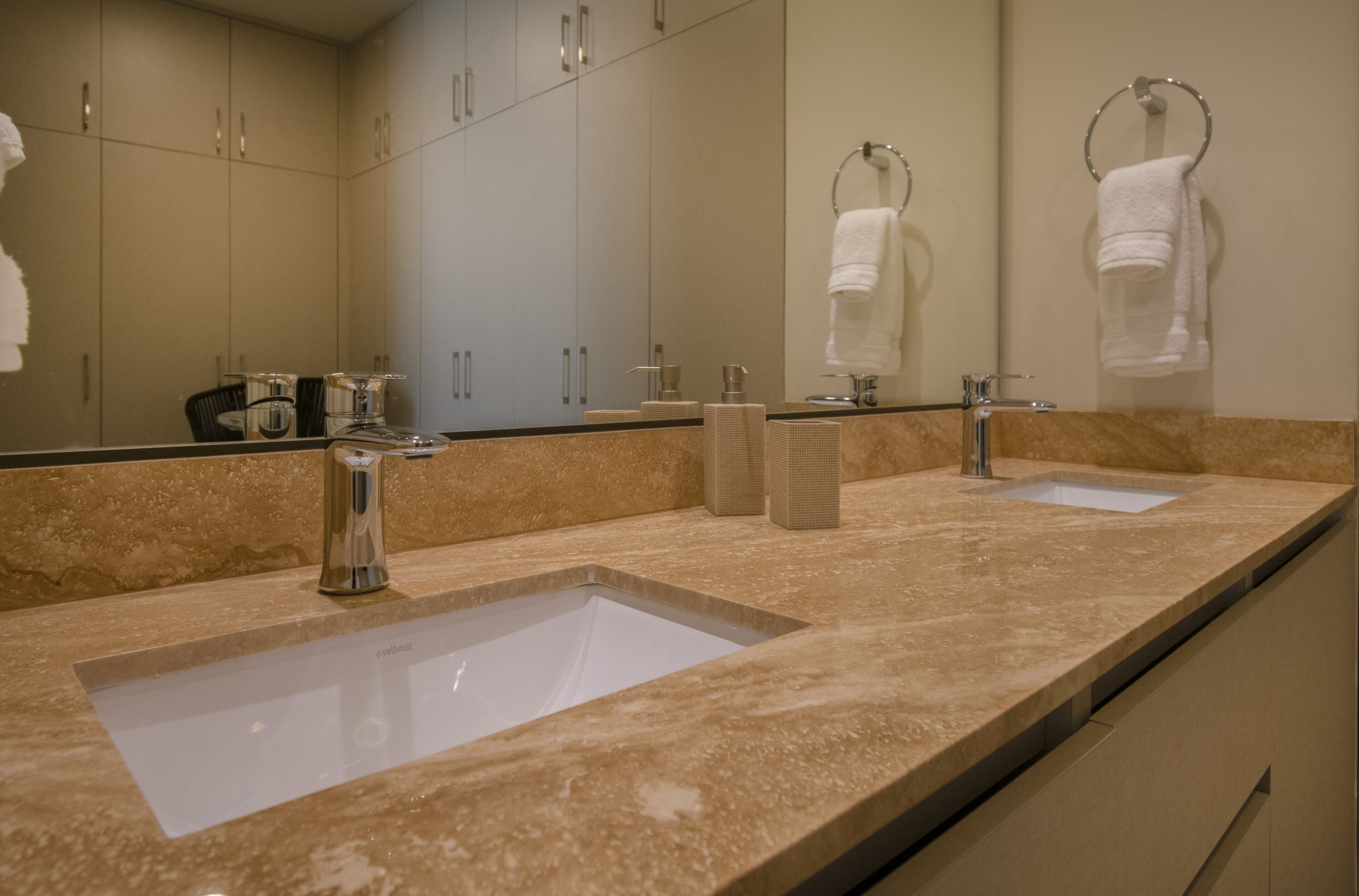 A modern bathroom with two sinks, a large mirror, and a towel rack.