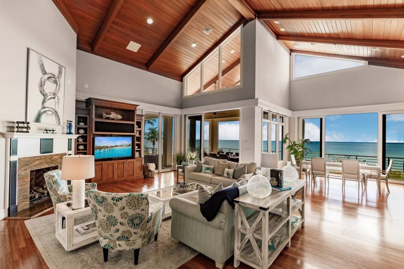 A spacious living room with a fireplace, comfortable seating, a television, and large windows offering ocean views.