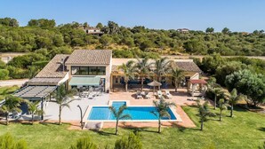 Une villa moderne dotée d’une piscine, d’un espace salon extérieur et offrant une vue sur les collines environnantes.