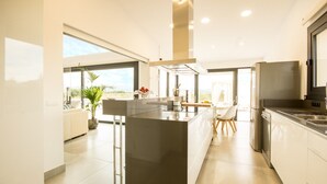 Une cuisine moderne dotée d’un îlot central, d’appareils électroménagers en acier inoxydable et de grandes fenêtres.