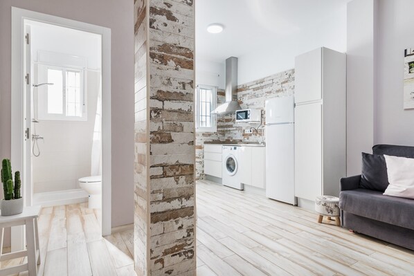 Eine moderne Wohnung mit Küche, einem grauen Sofa und einer weißen Tür.