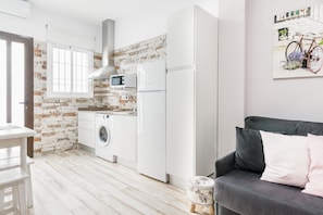 A compact kitchen with a washing machine, a built-in microwave, and a refrigerator.