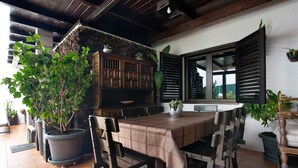 Un coin repas comprenant une table, des chaises, des plantes en pot et un mur en pierre.