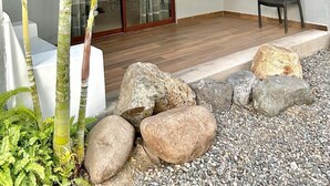 Un espacio exterior moderno con una hamaca, una silla y un pequeño jardín de rocas.