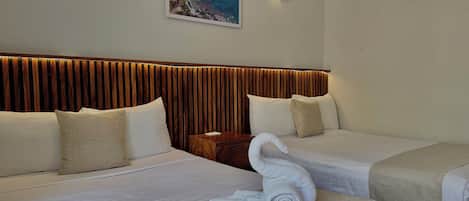 A hotel room with two beds, a wooden headboard, a wall-mounted air conditioner, and a framed picture.
