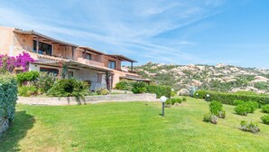 Une maison à deux étages avec un jardin, une piscine et une vue sur les collines.