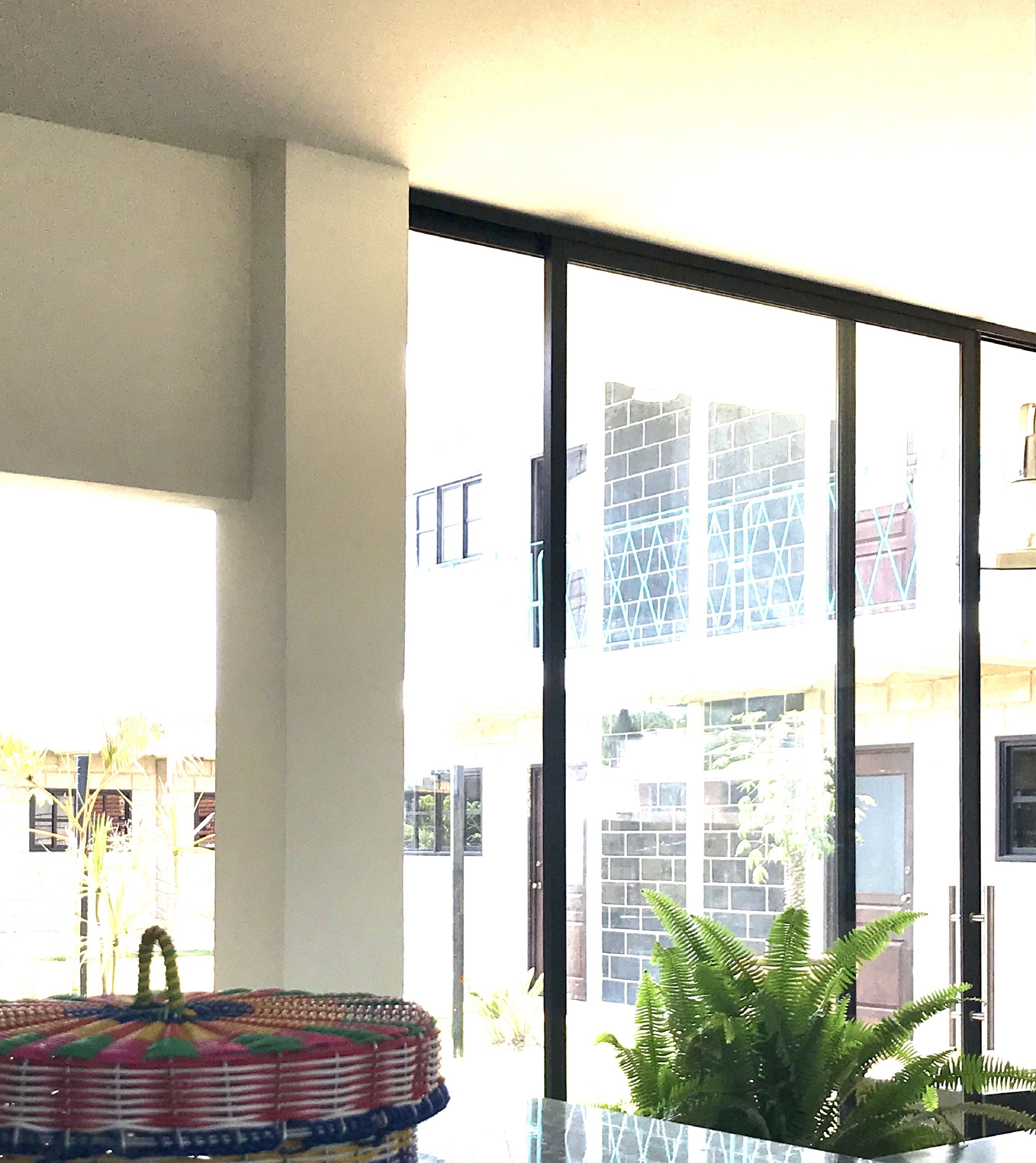 Una habitación con un ventanal amplio, una cesta tejida y una planta en maceta.