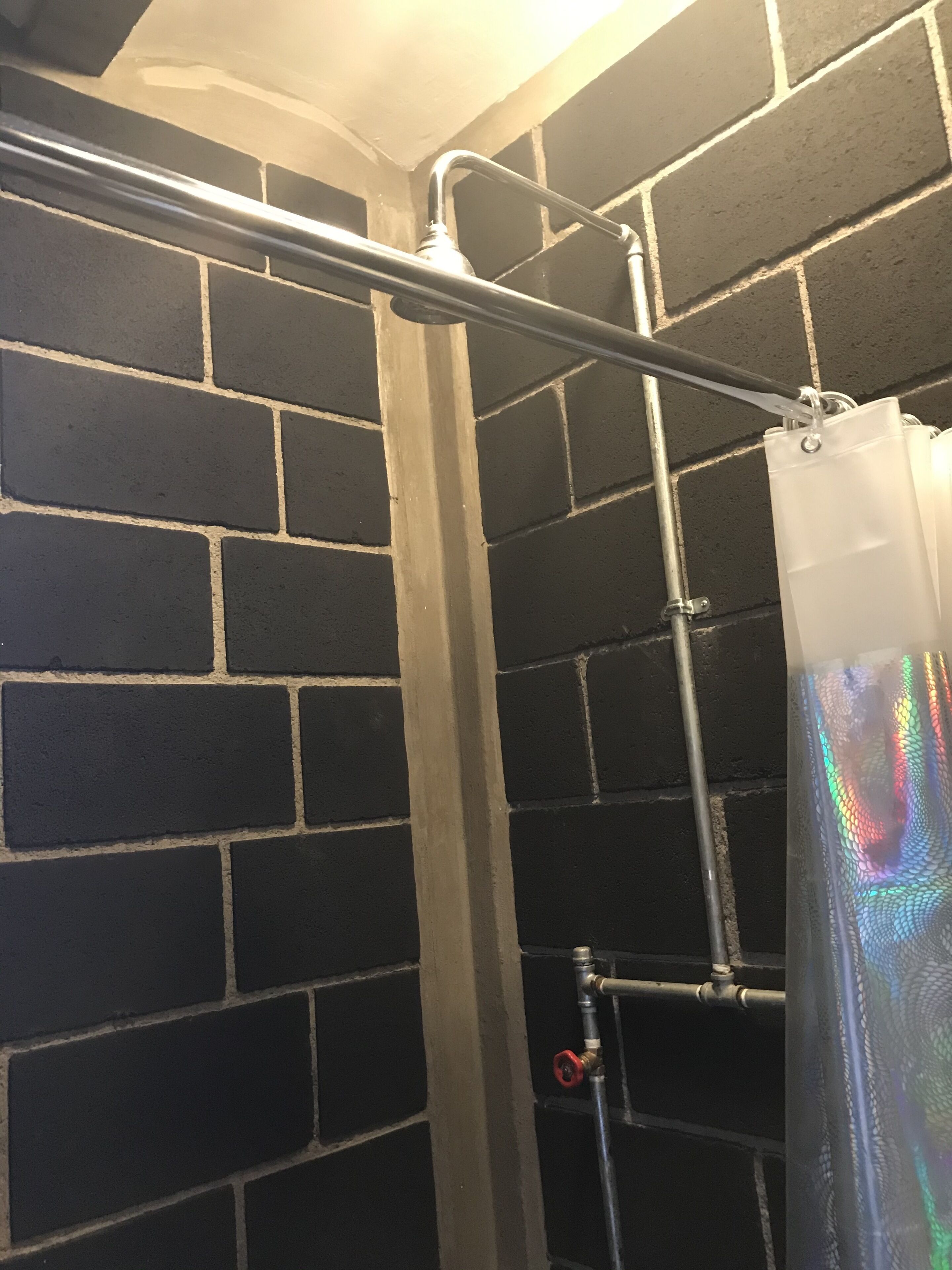 A shower area with a metal pipe and a shower curtain.