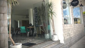 Een restaurant met glazen ingang, terras en potplanten.