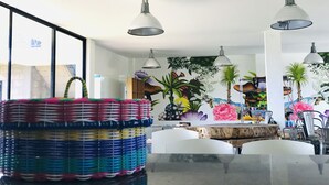 Een moderne eetruimte met een groot raam, witte stoelen, een centrale tafel en hangende pendellampen.