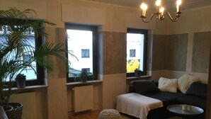 A room with a sofa, a small table, a potted plant, and a radiator.