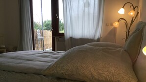 A bedroom with a bed, a bedside table, and a window with curtains.