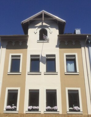Un edificio con fachada simétrica, múltiples ventanas y una entrada central con una bandera.