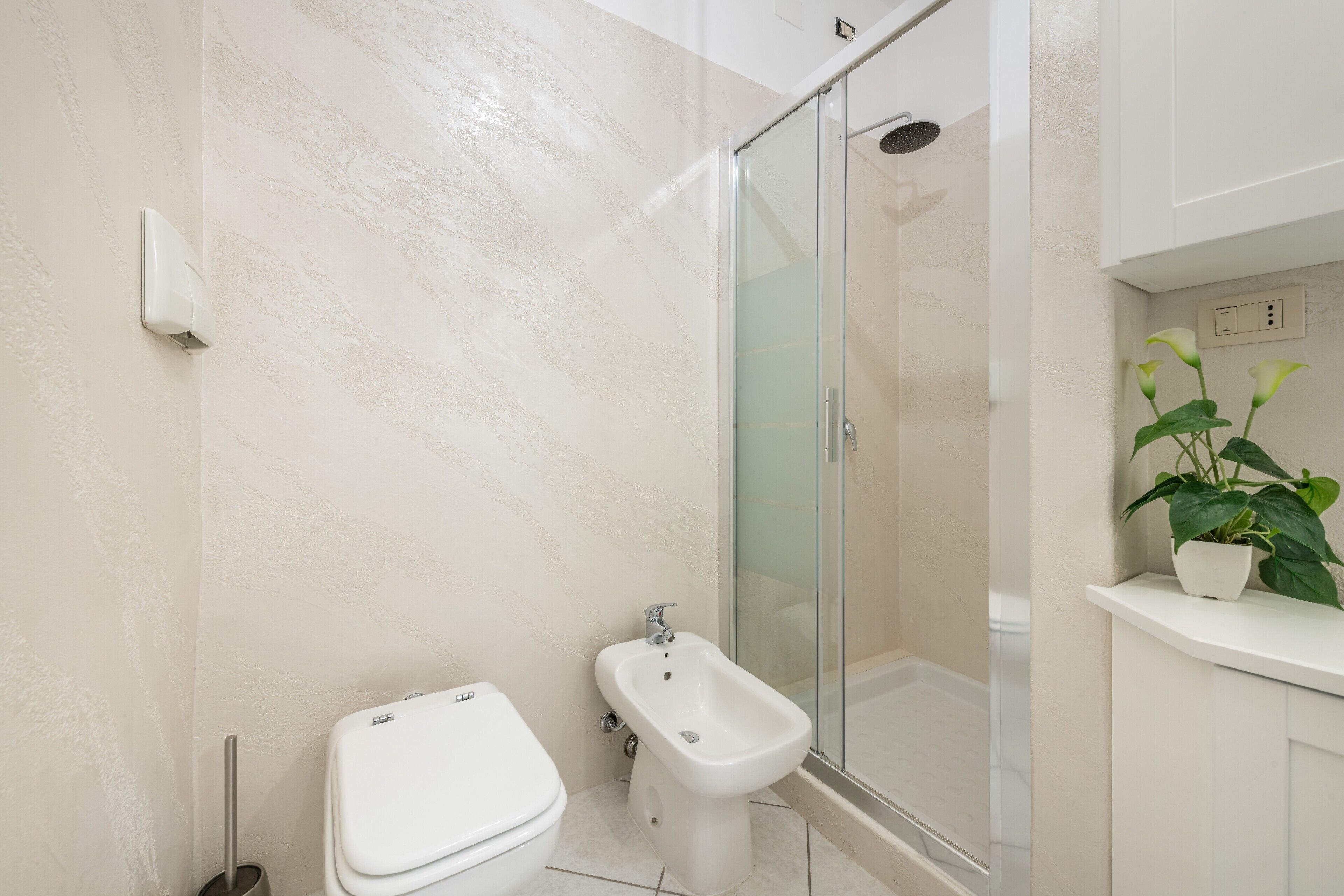 A bathroom with a toilet, bidet, and glass shower enclosure.