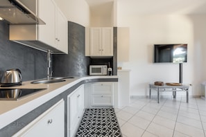 A modern kitchen with a microwave, kettle, and a small table with baskets.