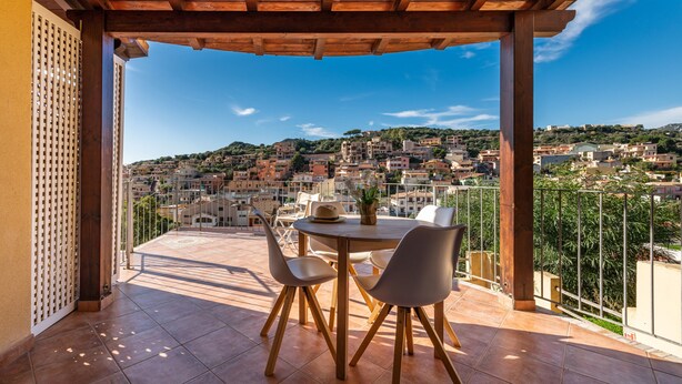 A covered outdoor dining area with a view of a hillside town. - Apartment "Suite Home Simius" Close to Beach with Terrace, Sea View & Air Conditioning (Villasimius)