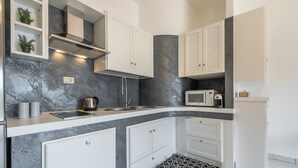 A modern kitchen with white cabinets, a black and white patterned rug, a microwave, and a kettle. - Apartment "Suite Home Simius" Close to Beach with Terrace, Sea View & Air Conditioning (Villasimius)