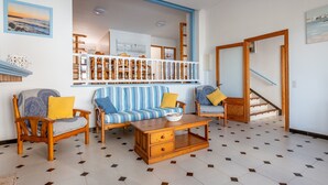 Una sala de estar con un sofá, sillones, una mesa de centro y una escalera.
