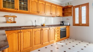 Una cocina con armarios de madera, encimera de granito, fregadero, estufa y ventana.