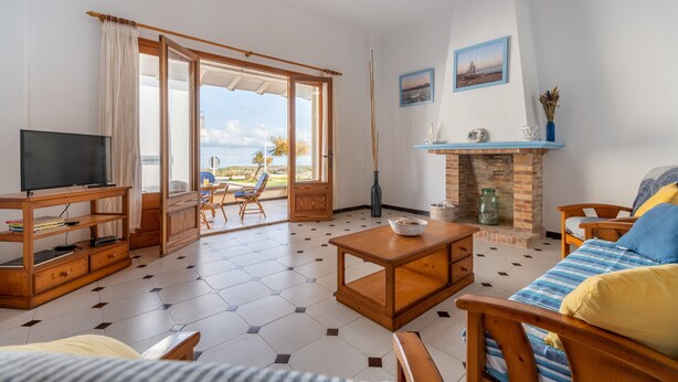 Una sala de estar con televisor, muebles de madera, chimenea y vistas al exterior.