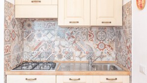 Une cuisine avec des carreaux décoratifs, des armoires en bois, une cuisinière à gaz et un évier.
