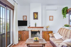 Uma sala de estar com lareira, sofá, televisão e janela com vista.