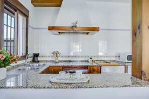 A kitchen with granite countertops, stainless steel appliances, and a wooden ceiling.