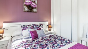 Een slaapkamer met een bed, nachtkastjes, een lamp en een wanddecoratie.
