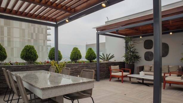 An outdoor patio with a dining table and chairs, a sofa, and a potted plant.