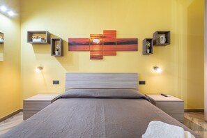 A bedroom with a bed, bedside tables, a wall-mounted artwork, and a nightstand.