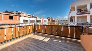 A wooden balcony with a metal railing, a view of neighboring buildings, and a clear blue sky. - Spacious Holiday Home “Paradise Home” with Wi-Fi & Balcony (Quartu Sant'Elena)