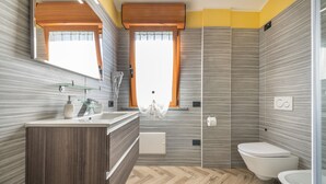 A modern bathroom with a wooden vanity, a toilet, and a shower area. - Spacious Holiday Home “Paradise Home” with Wi-Fi & Balcony (Quartu Sant'Elena)