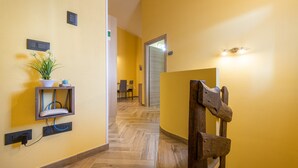 A hallway with a wooden chair, a potted plant, and a wall-mounted shelf. - Spacious Holiday Home “Paradise Home” with Wi-Fi & Balcony (Quartu Sant'Elena)