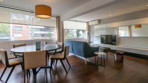 A modern dining area with a round table, chairs, a blue sofa, and a television. - w* | Luxury 2BR in Blas Cerdeña, San Isidro (Cercado de Lima)