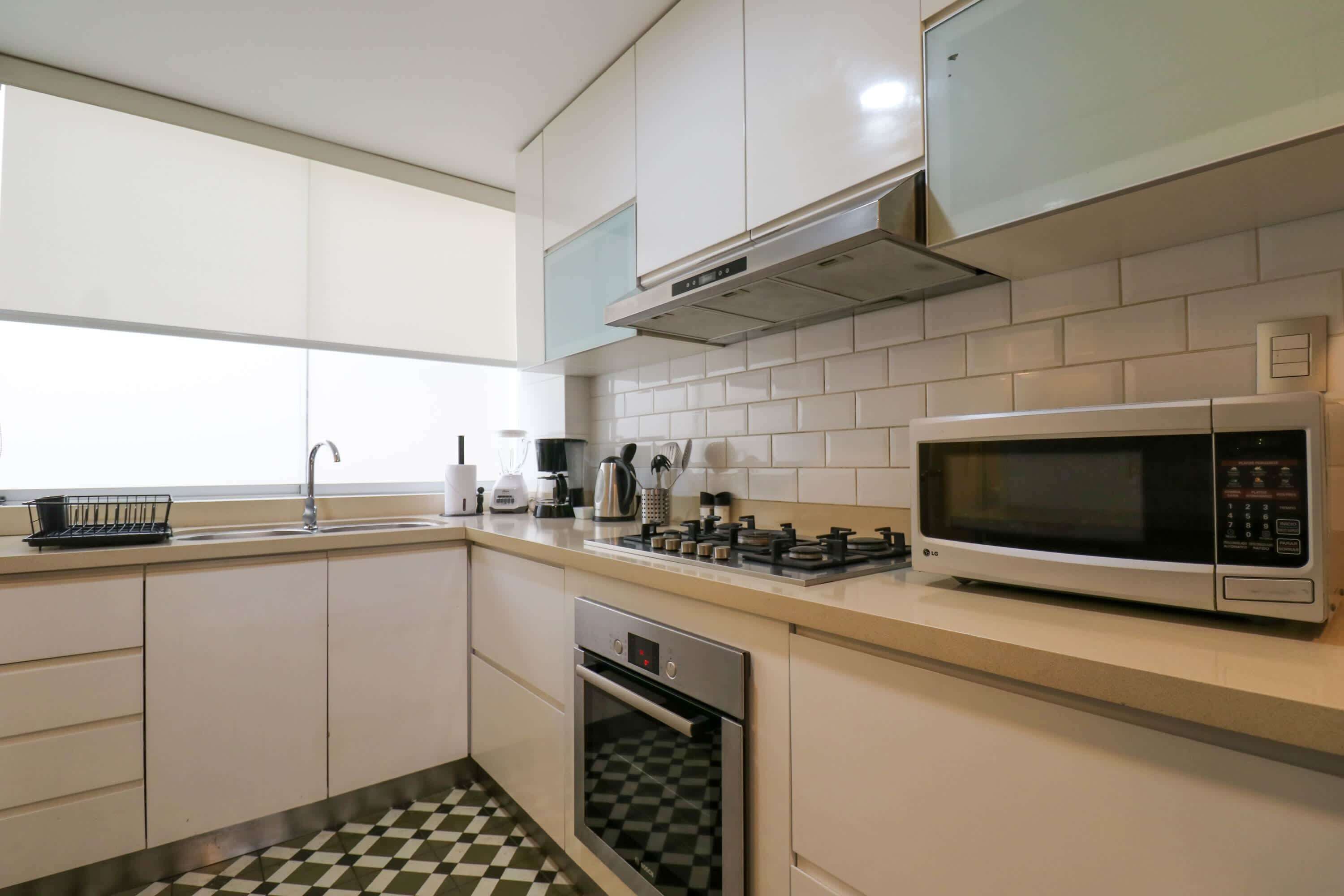 A modern kitchen with white cabinets, a microwave, a gas stove, and a dishwasher.