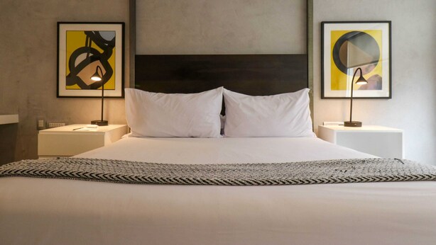 A hotel room with a large bed, two bedside tables, and abstract artwork on the walls. - w* | Luxury 2BR in Blas Cerdeña, San Isidro (Cercado de Lima)