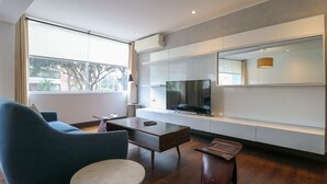 A modern living room with a sofa, a coffee table, a TV, and a large window. - w* | Luxury 2BR in Blas Cerdeña, San Isidro (Cercado de Lima)