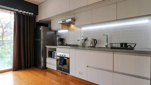A modern kitchen with stainless steel appliances, white cabinets, and a granite countertop. - w* | Elegant Loft Near Boardwalk in Barranco (Barranco)