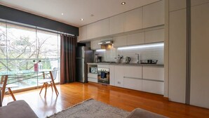 A modern kitchen with white cabinets, stainless steel appliances, and a large window offering a view of trees. - w* | Elegant Loft Near Boardwalk in Barranco (Barranco)