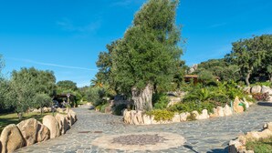 A stone pathway leading to a building with a traditional roof, surrounded by greenery and rocks. - Résidence Villa Smeralda Executive – Upscale Apartment with Pool near Olbia (Telti)